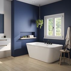 a white bath tub sitting next to a window in a blue bathroom with wooden floors