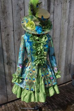 a dress made out of fabric with feathers and flowers on the front, sitting on a stand