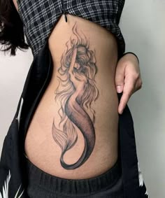 a woman's stomach with a tattoo design on the belly and her hair blowing in the wind