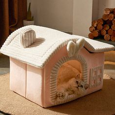 an orange cat laying in a pink house shaped like a doghouse with its front door open