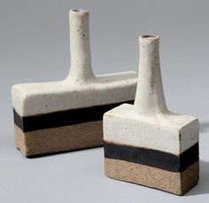 two white and black vases sitting next to each other