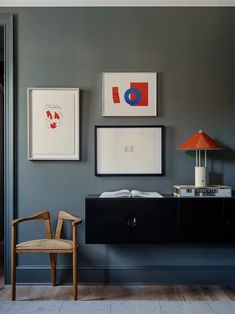 a living room with blue walls and pictures on the wall, chair and lamp in foreground