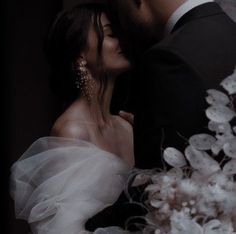 a bride and groom kissing in front of a bouquet of white flowers on their wedding day