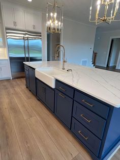 a large kitchen with blue cabinets and white counter tops, an island in the middle