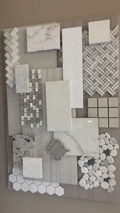 some white and grey tiles are on the wall next to each other, with different shapes and sizes