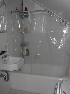 a bathroom with a sink, toilet and bathtub covered in clear shower curtaines