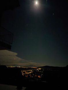 the moon is shining brightly in the night sky over a cityscape and hills