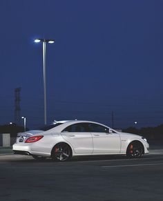 a white car parked in front of a street light at night with its lights on