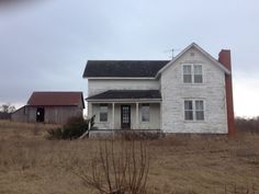 an old white house sitting on top of a dry grass field