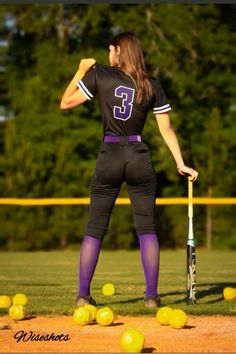 a woman holding a baseball bat on top of a field filled with yellow softball balls