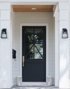 a black front door with two lights on each side and a white wall behind it