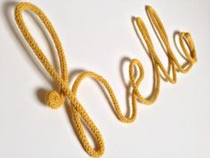 the word hello written in crochet on a white surface with a yellow rope