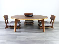 a wooden table with two chairs and a bowl on top of it in front of a white wall