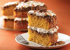 a piece of cake with icing and pecans on a plate next to it