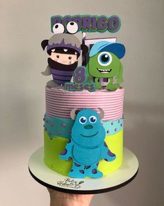 a hand holding up a cake with monsters on it