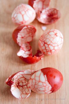 several pieces of red and white food on a wooden table with one piece peeled off