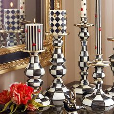 black and white checkered candlesticks are sitting on a table in front of a mirror