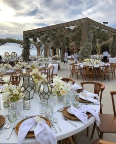 an outdoor dining area with tables and chairs set up for a formal function at the beach