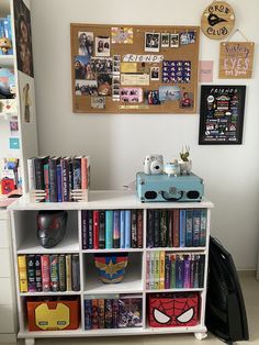 a book shelf filled with lots of books next to a wall covered in pictures and magnets