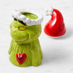 a green grin face planter next to a red vase with a santa hat on it