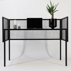 a computer desk with a laptop on it and a potted plant next to it