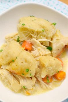 a white plate topped with dumplings covered in cheese and carrots on top of a table