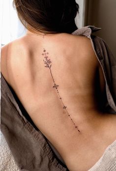 the back of a woman's neck with a flower tattoo on her left side