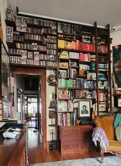 a living room filled with lots of books on top of a wooden shelf next to a doorway