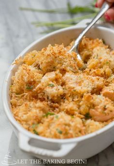 a close up of a casserole in a white dish with a spoon sticking out of it