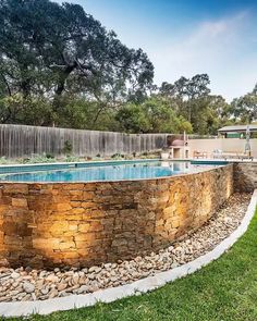 a stone wall around a pool in a backyard