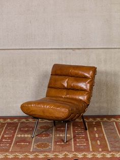 a brown recliner chair sitting on top of a rug next to a white wall