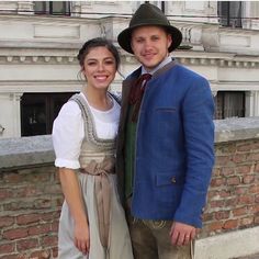 a young man and woman dressed in period clothing posing for a photo together on a brick wall