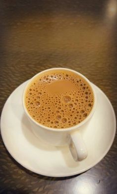 a white cup filled with liquid on top of a saucer