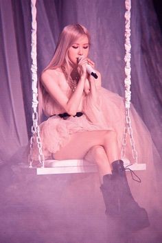 a woman sitting on a swing holding a microphone