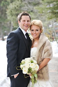 a bride and groom standing in the snow