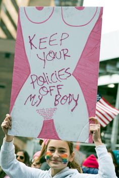 a woman holding up a sign that says keep your police officers off my boy on it