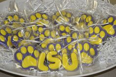 yellow and blue dog paw cookies wrapped in clear cellophane on a white plate