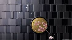 a vase with pink flowers on it next to a black tiled wall