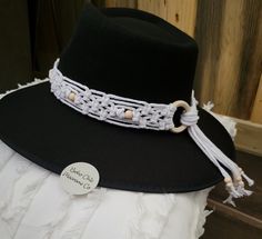 a black hat with a white ribbon around the brim and some beads on it