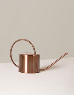 a metal watering can sitting on top of a table