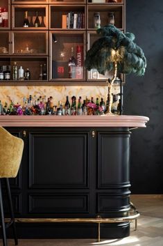 an elegant bar with black cabinets and gold trimmings has a palm tree on the counter