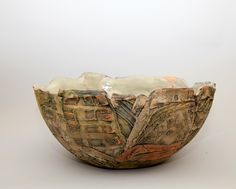 a bowl that is made out of clay and has buildings on the outside, in front of a white background