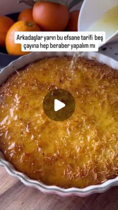 a cake in a pan on top of a wooden table next to some oranges