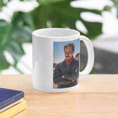 a white coffee mug with an image of a man in leathers on it sitting on a table