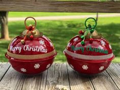 two red christmas baubles sitting on top of a wooden table next to each other