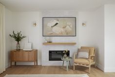 a living room with a fireplace, chair and painting on the wall above it's mantle