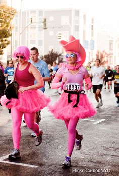 two women in pink costumes are running down the street