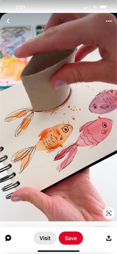 someone is using a mouse to draw fish on a notepad with watercolors