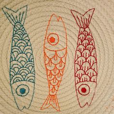 three colorful fish on a white surface with blue and orange lines in the middle,