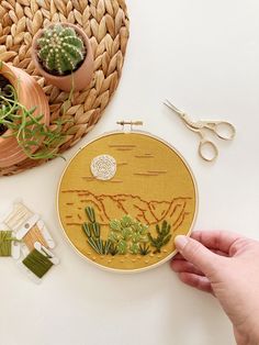 someone is working on an embroidered desert scene